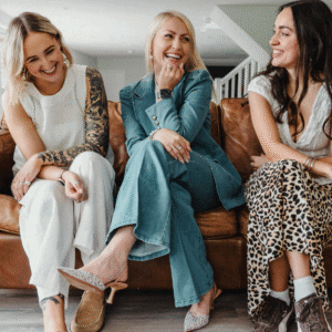 KW Marketing team members sitting on a leather sofa, smiling and chatting during a relaxed brand photoshoot in Exeter.
