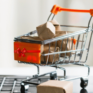 Mini shopping cart filled with wrapped Christmas parcels on a laptop keyboard, symbolising Q4 food and drink marketing and online sales