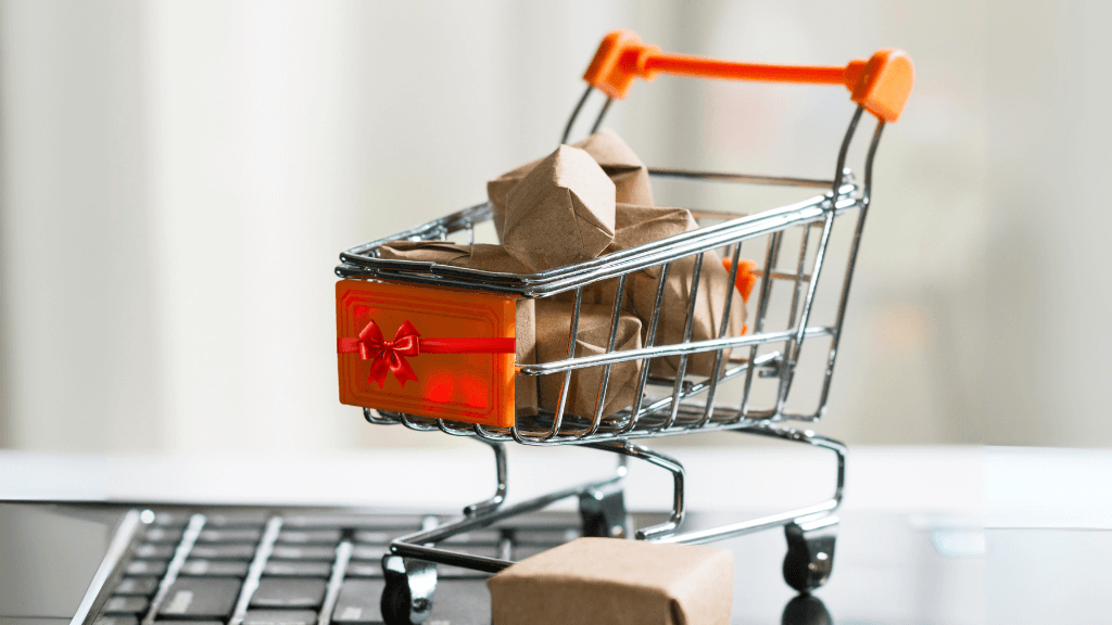 Mini shopping cart filled with wrapped Christmas parcels on a laptop keyboard, symbolising Q4 food and drink marketing and online sales